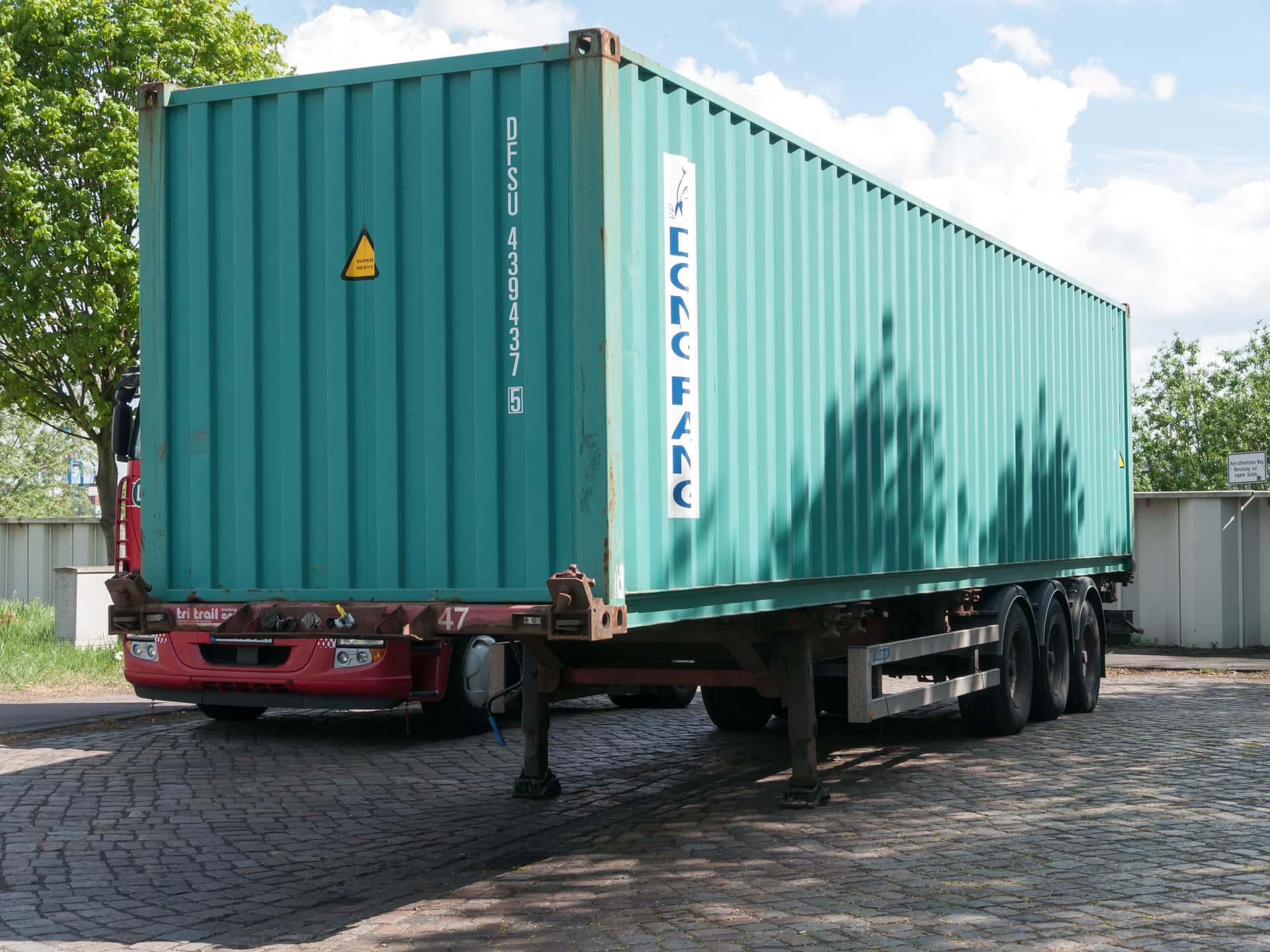 A green 40-foot dry container on a skeletal trailer in the Port of Hamburg