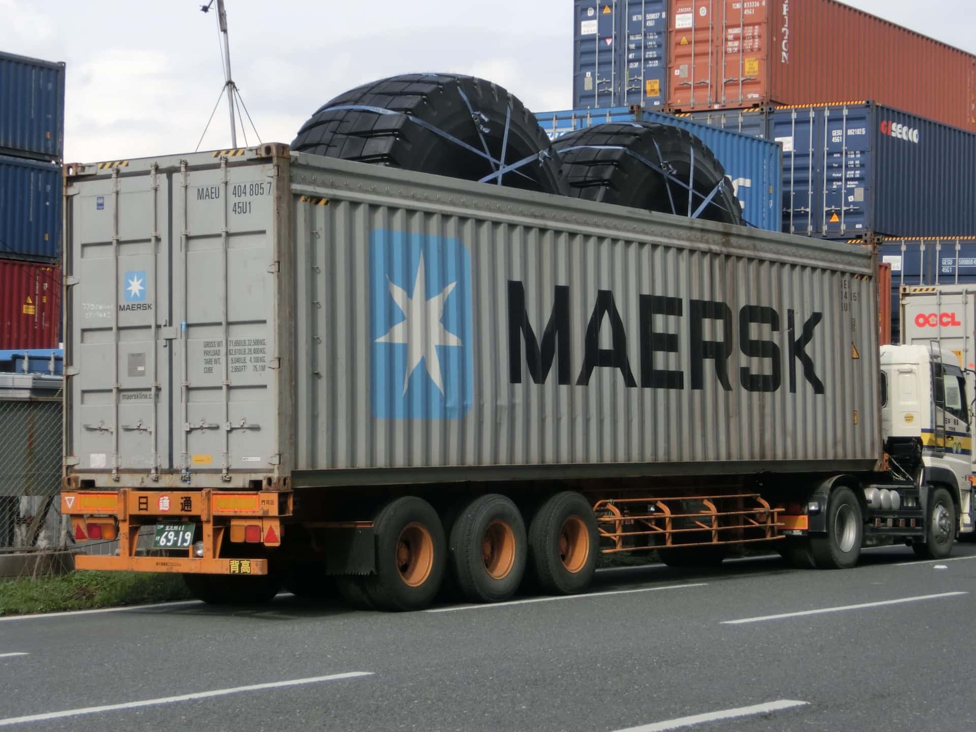 A 40-foot high cube open top container on a trailer with oversized tyres lashed through the open roof