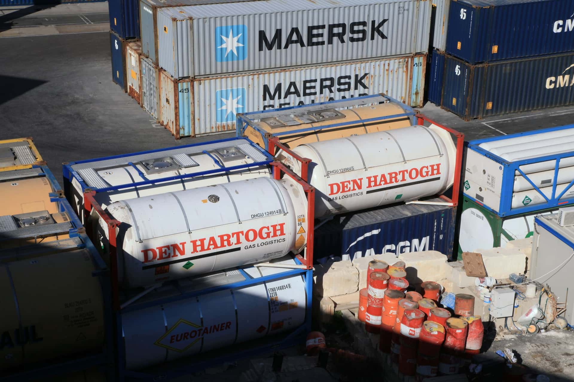 ISO tank containers in their frames stacked beside dry boxes at Malta Freeport in low sun