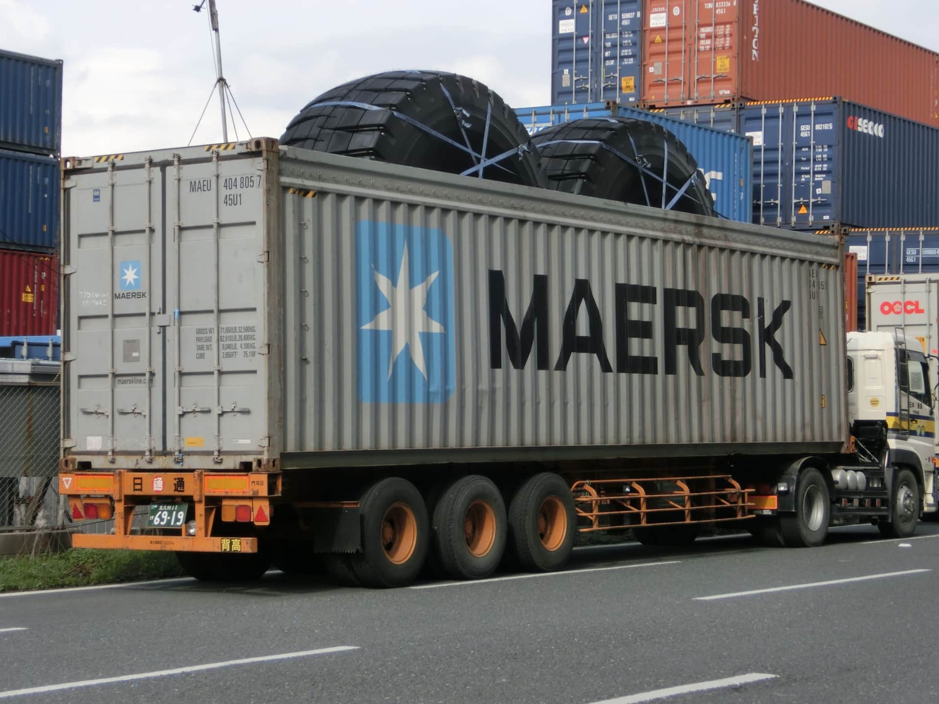 A 40-foot high cube open top container on a trailer with oversized tyres lashed through the open roof