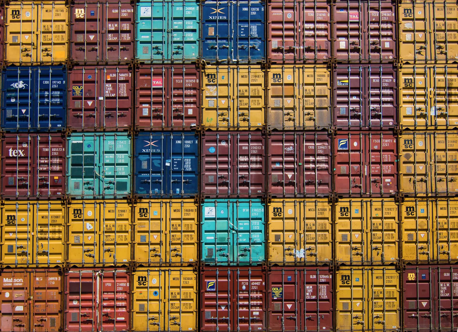 Aerial view of colour-blocked container stacks and rubber-tyred gantry cranes at a terminal