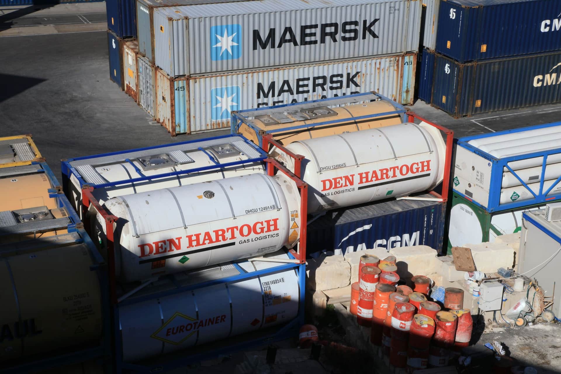 ISO tank containers in their frames stacked beside dry boxes at Malta Freeport in low sun