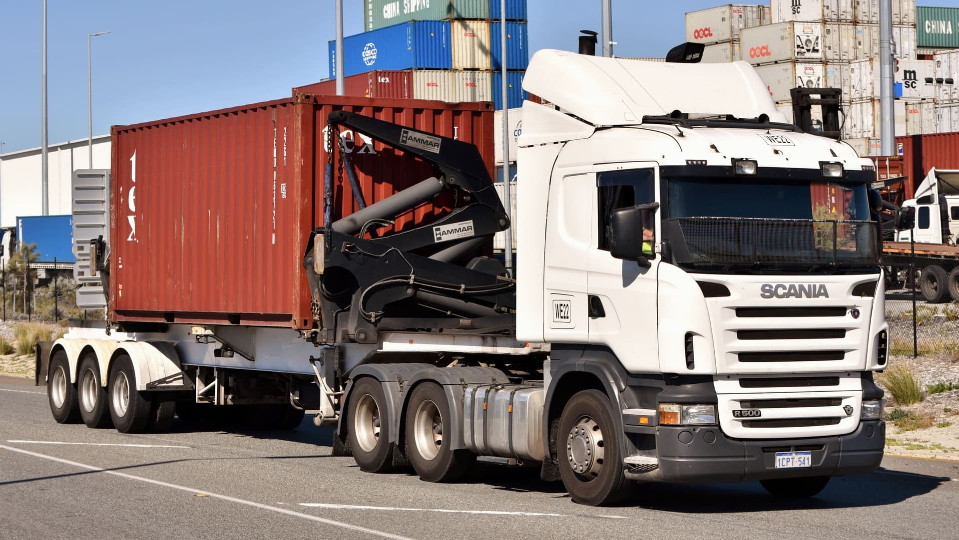 A sidelifter trailer carrying a 20-foot container along a port road in Fremantle